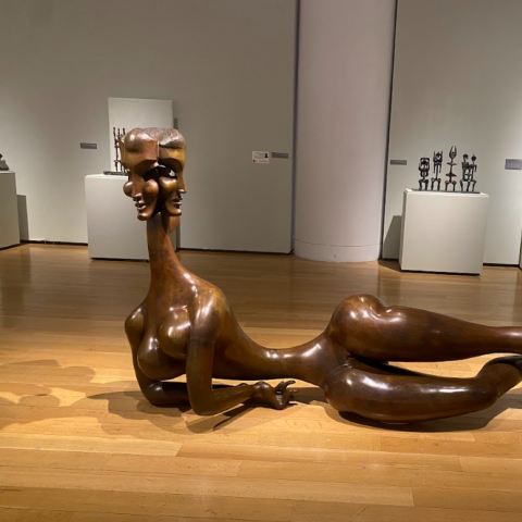 在艺术画廊展出的木制雕塑，背景是一个人.